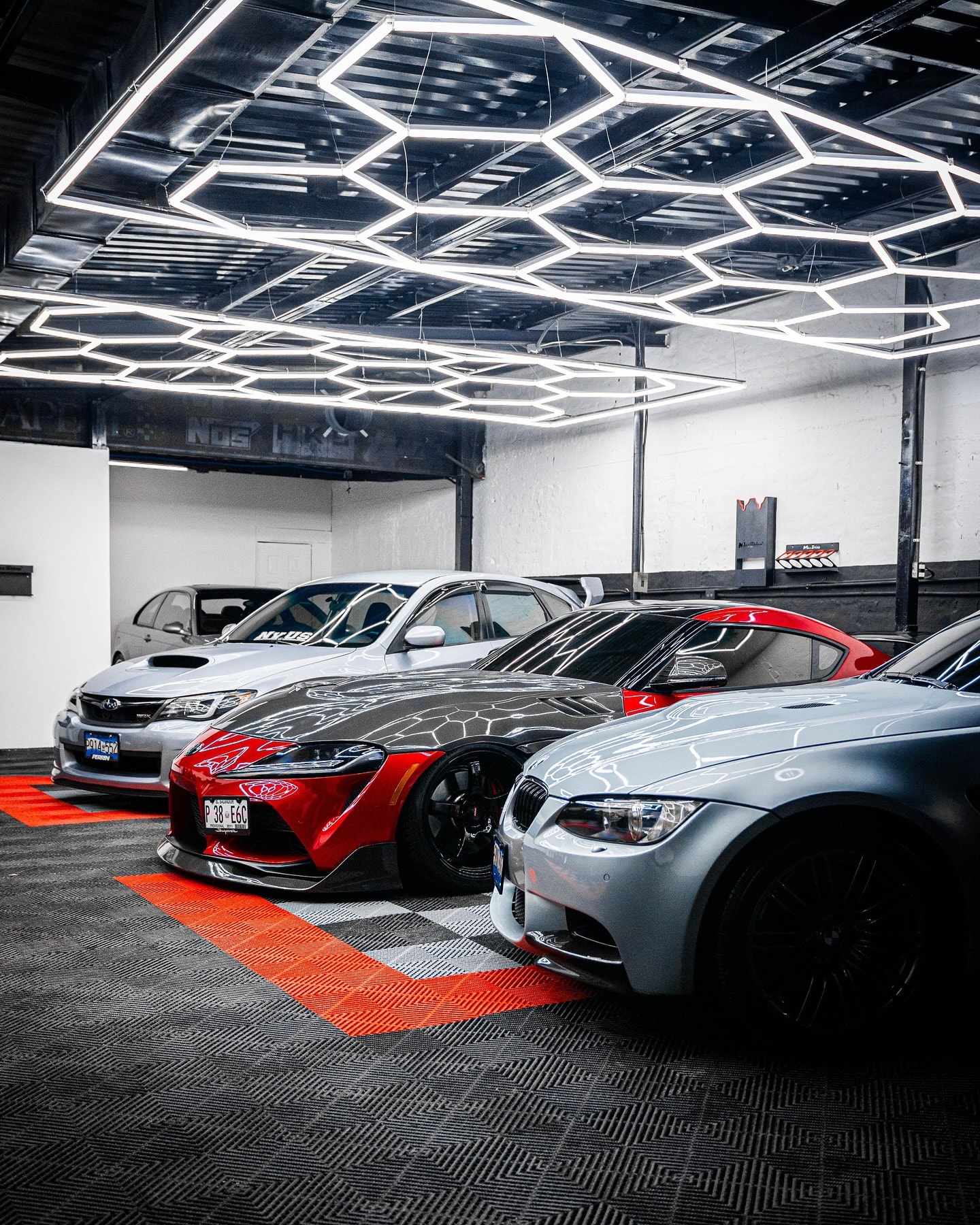 Bahía de CarLab con tres autos bajo luces hexagonales